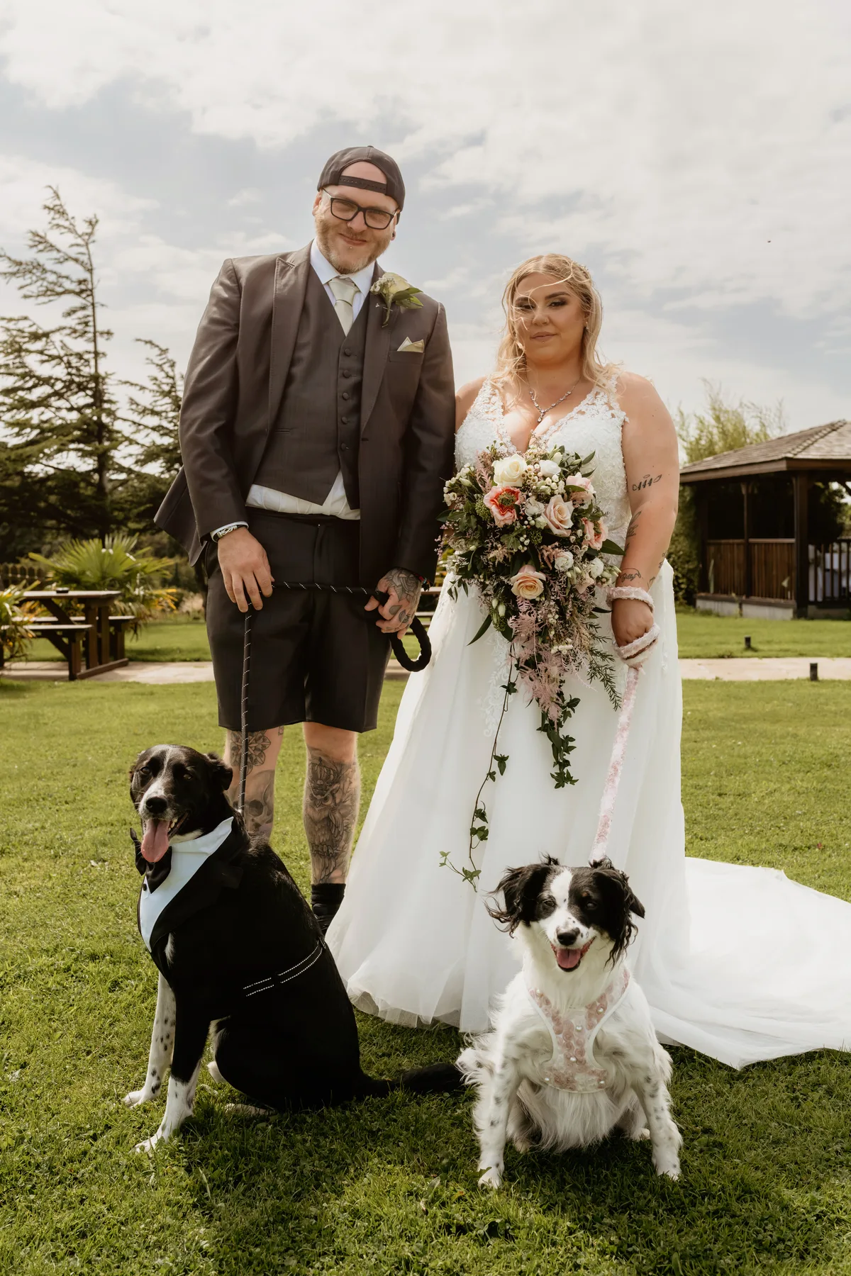 A couple on the lawn with their two dogs beside them