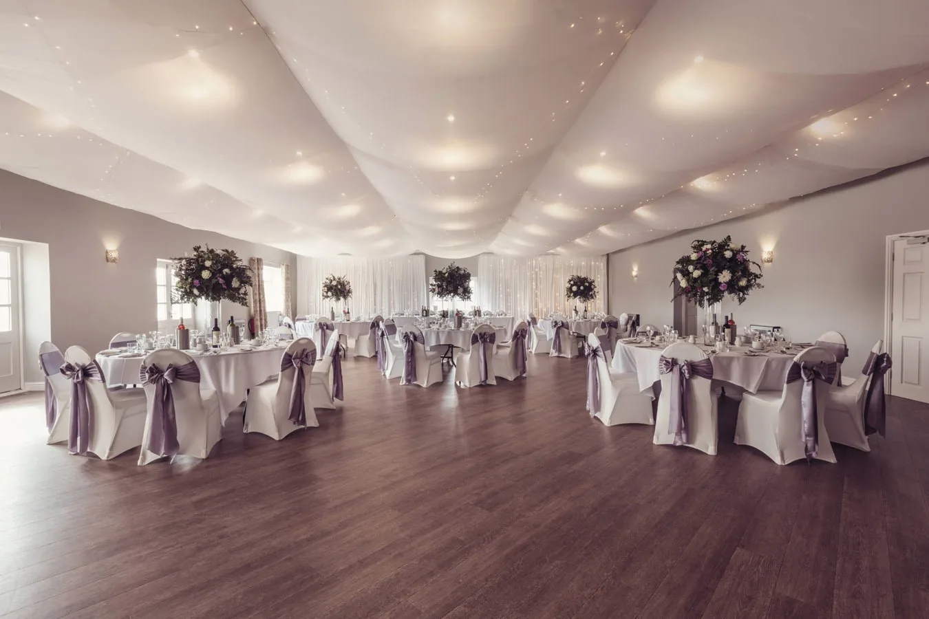 The Hawthwaite Suite laid for a wedding breakfast, tall flowers on every table