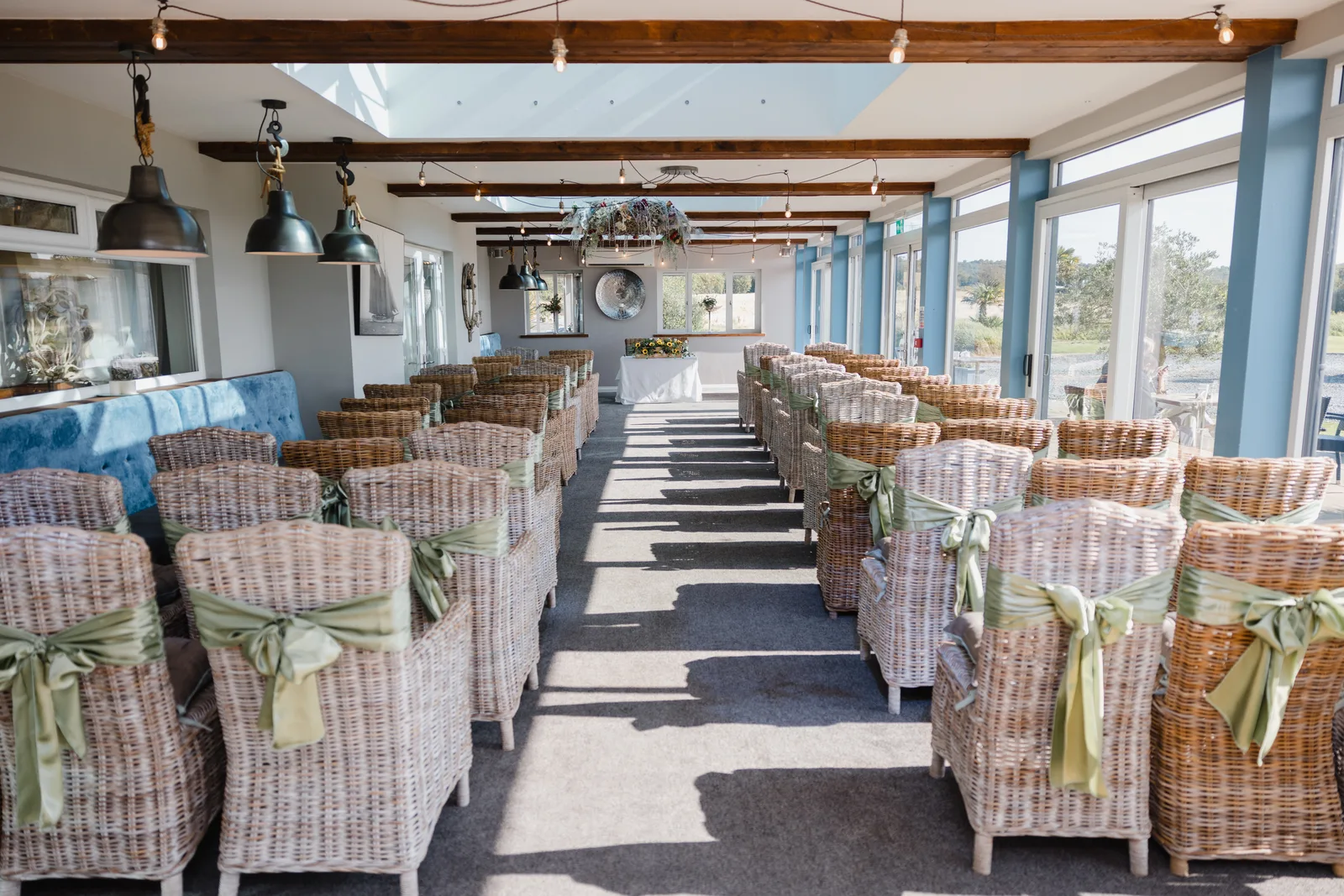 Wicker chairs with sage sashes lining the aisle in the Terrace Room